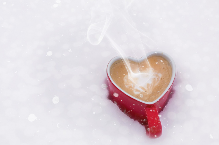 Sydämen muotoinen kahvikuppi hangessa.