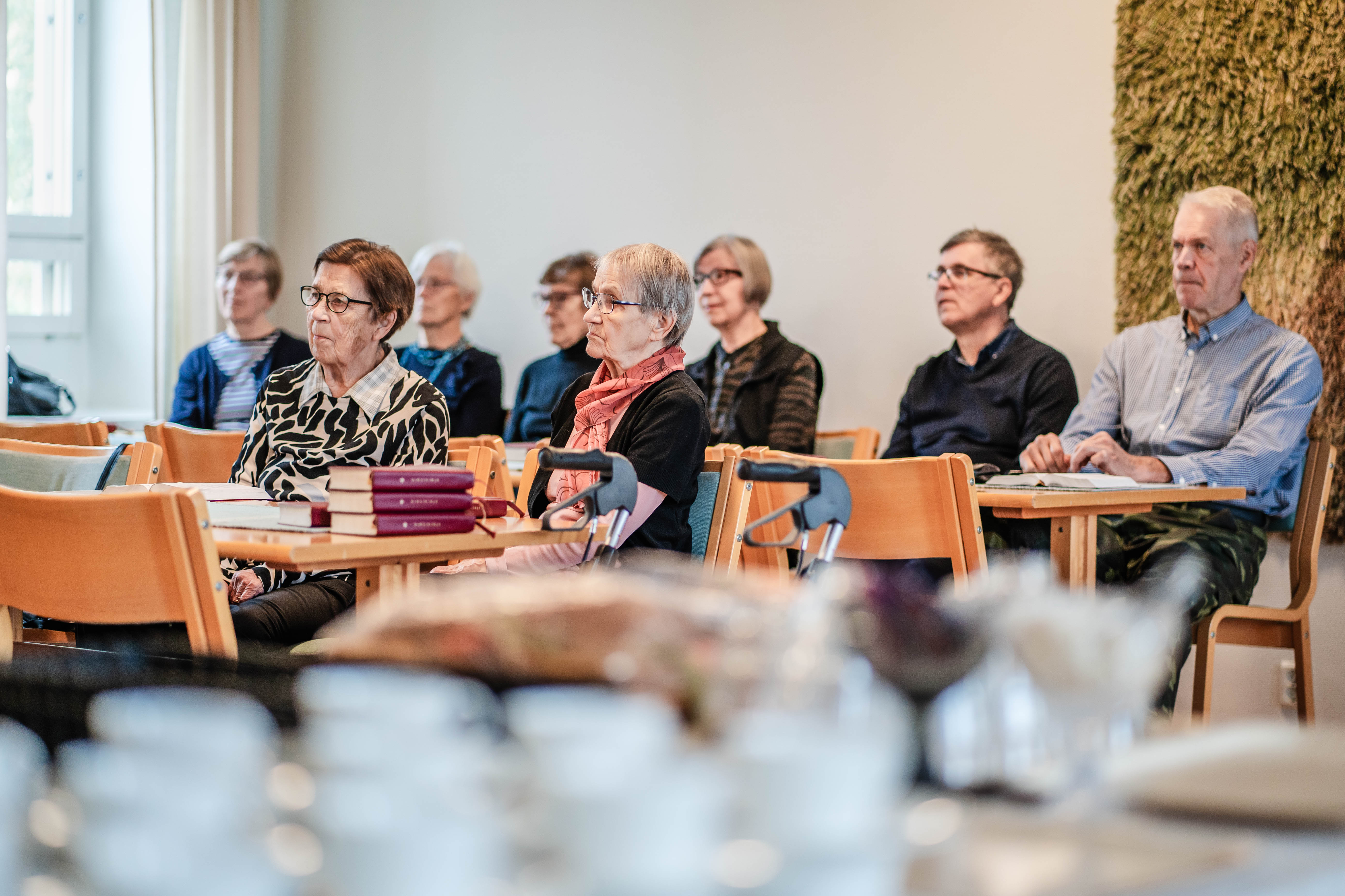 Yleisöä istumassa pöytäryhmissä ja kuuntelemassa esitystä