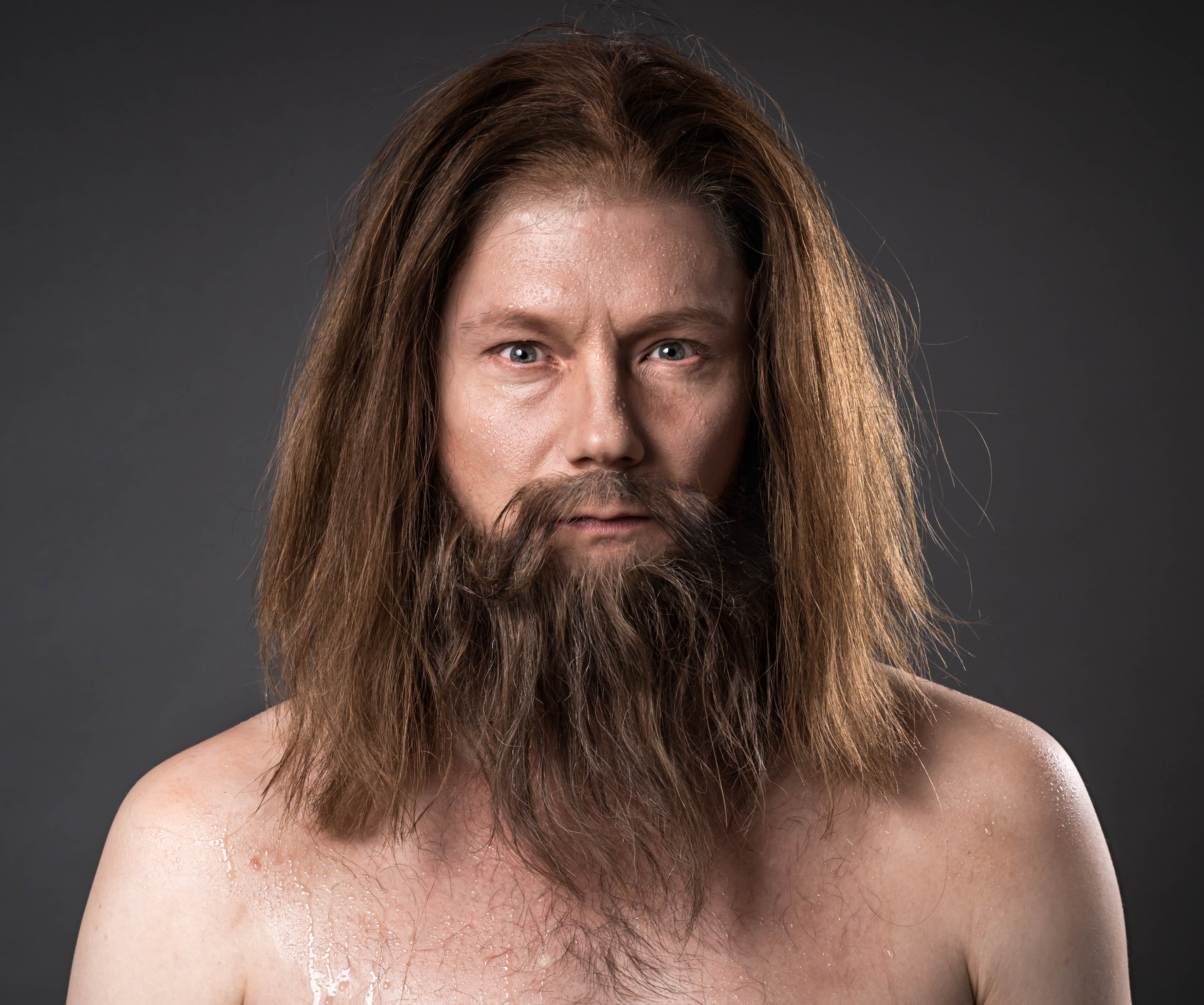 Lähikuva pitkätukkaisesta miehestä, joka katsoo suoraan kameraan.