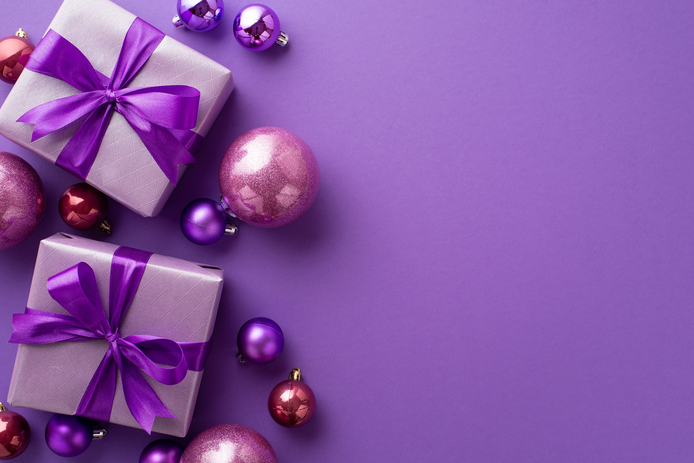 Lahjapaketit ja joulupallot violetilla taustalla