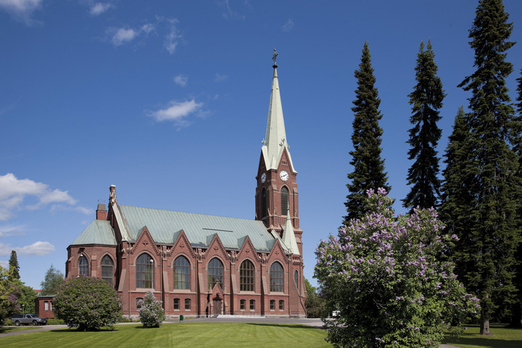 Mikkelin tuomiokirkko kesäpäivänä. Edessä tuomiokirkon puisto ja vanhat kuuset.