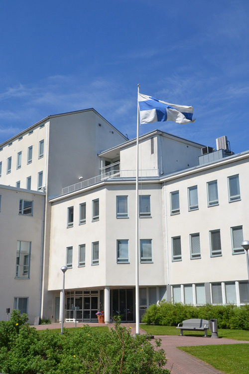 Mikkelin seurakuntakeskus sisäpihalta päin kuvattuna kesällä. Pihassa lipputanko ja lippu liehuu.