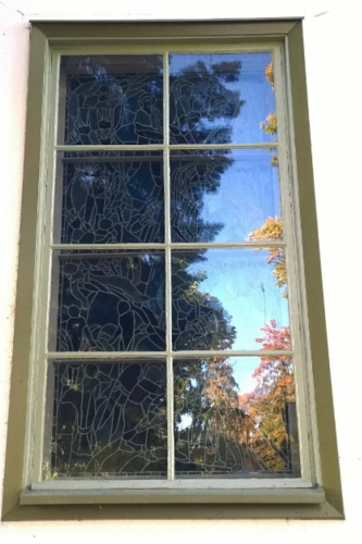 Ikkuna, josta heijastuu syksyinen maisema.