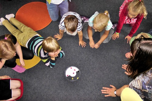 Lapset pelaavat peliä ringissä lattialla.