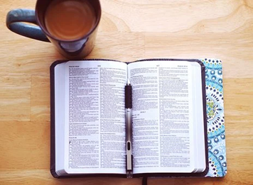 Kuvassa Raamattu kahvikupin äärellä