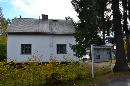 Pitkäjärven seurakuntakoti syksyisessä maisemassa. Edessä ilmoitustaulu.