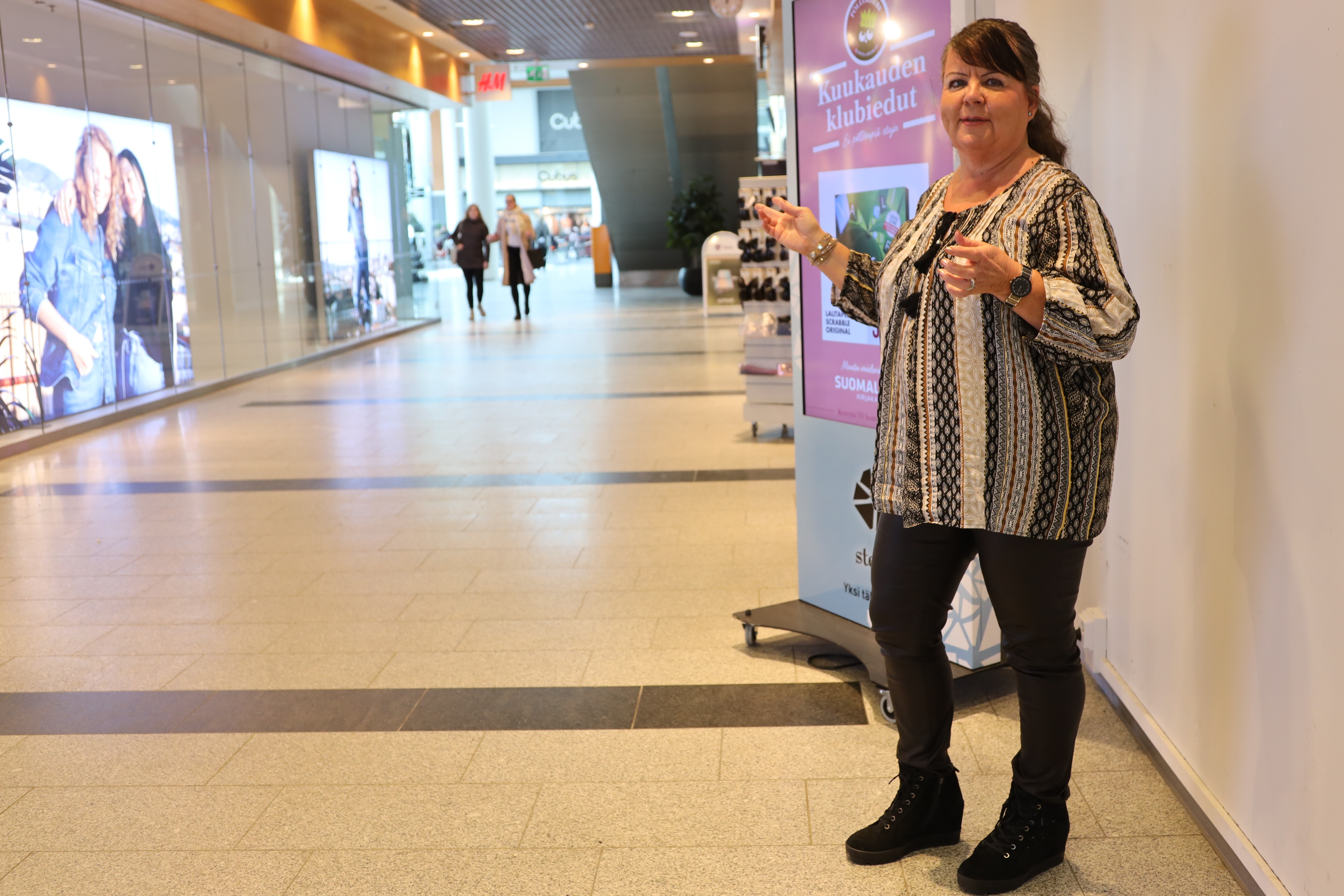 Kauppakeskus Stellan asiakkuuspäällikkö Marja-Leena Koukonen seisoo kauppakeskuksen aulassa kädet levällään.