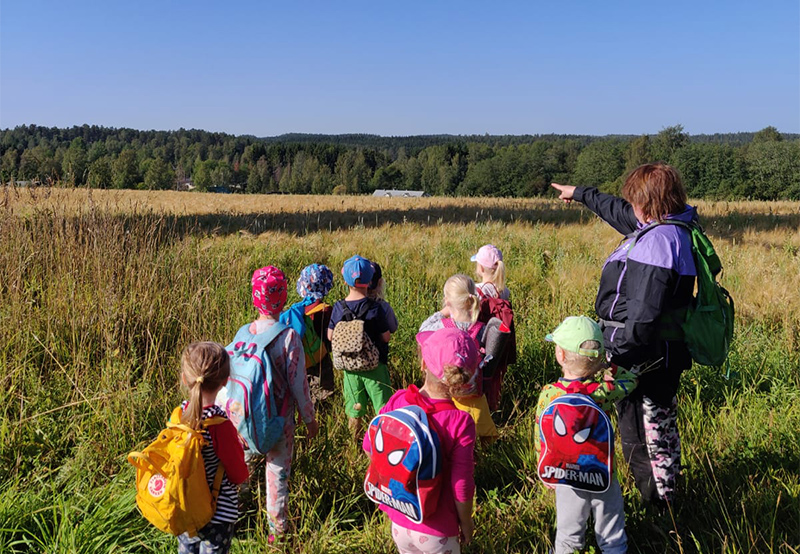 Lapset pellon laidassa Eila-ohjaajan kanssa Mikkelin Otavassa.