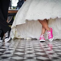Kuvassa näkyy hääparin jalat ja morsiamen hääpuvun helmoja, parilla on tennarit jalassa.