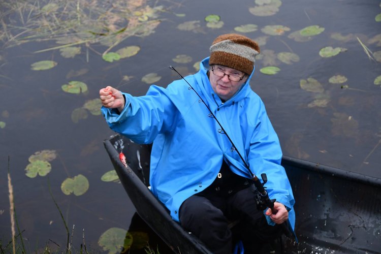 Liisa Heikkinen veneessä sininen sadetakki päällä kalassa.