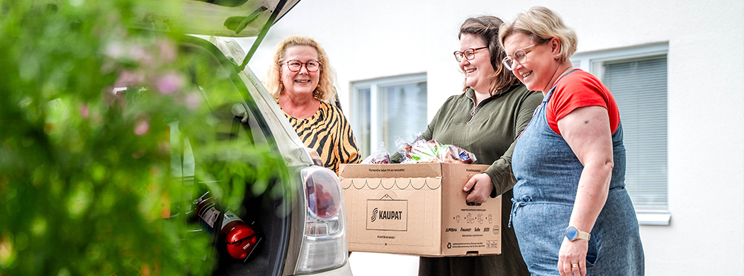 Diakoniatyöntekijöitä purkamassa leipälahjoitusta autosta.